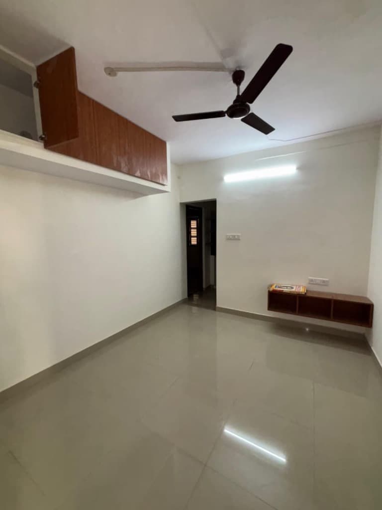 SLN Homes spacious well-lit room with vitrified tiles and overhead storage cabinets